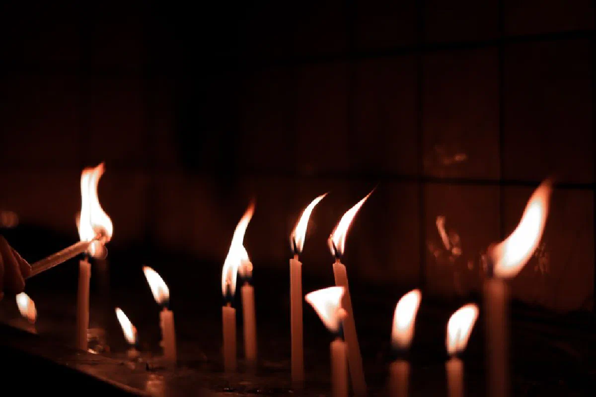 A serene image of candles burning brightly, casting a warm glow in a dimly lit space.