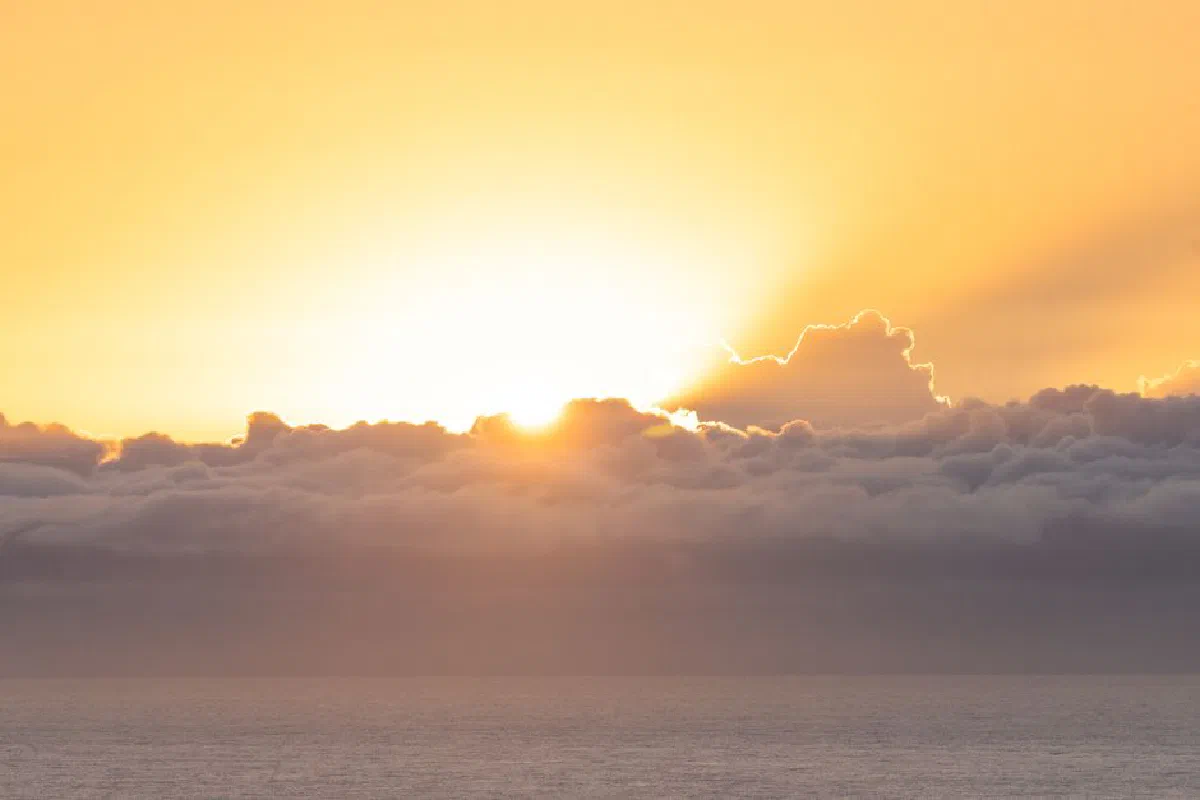 Stunning ocean sunrise with golden hues and dramatic clouds creating a serene atmosphere.