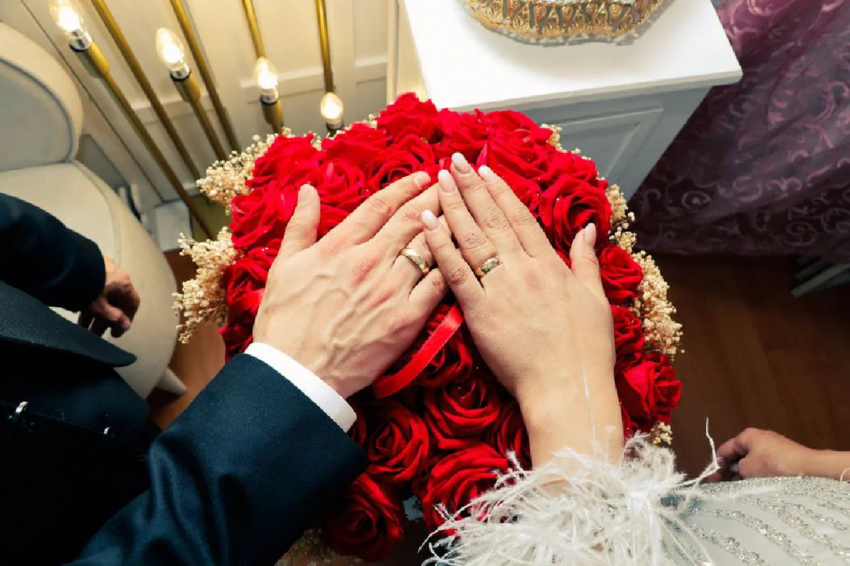 Wedding rings on a bouquet of red roses, symbolizing love and commitment.