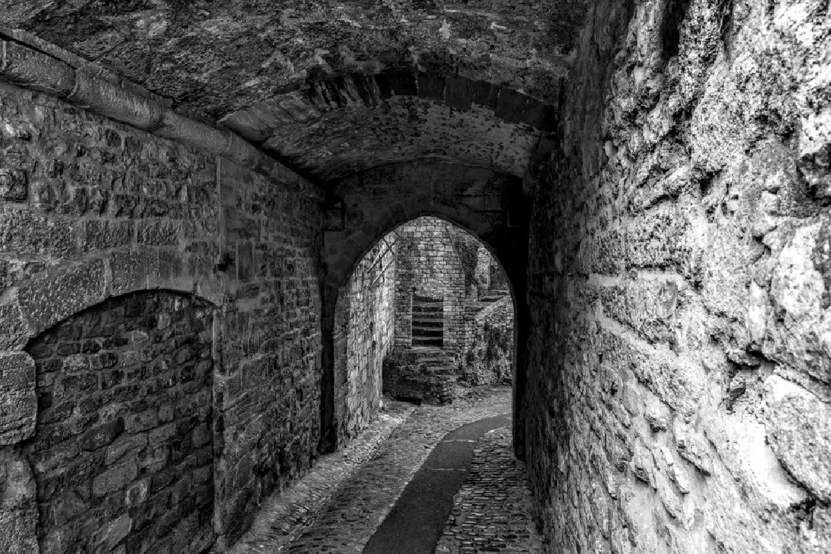Black and white view of a medieval stone alleyway in Vaison-la-Romaine, France.