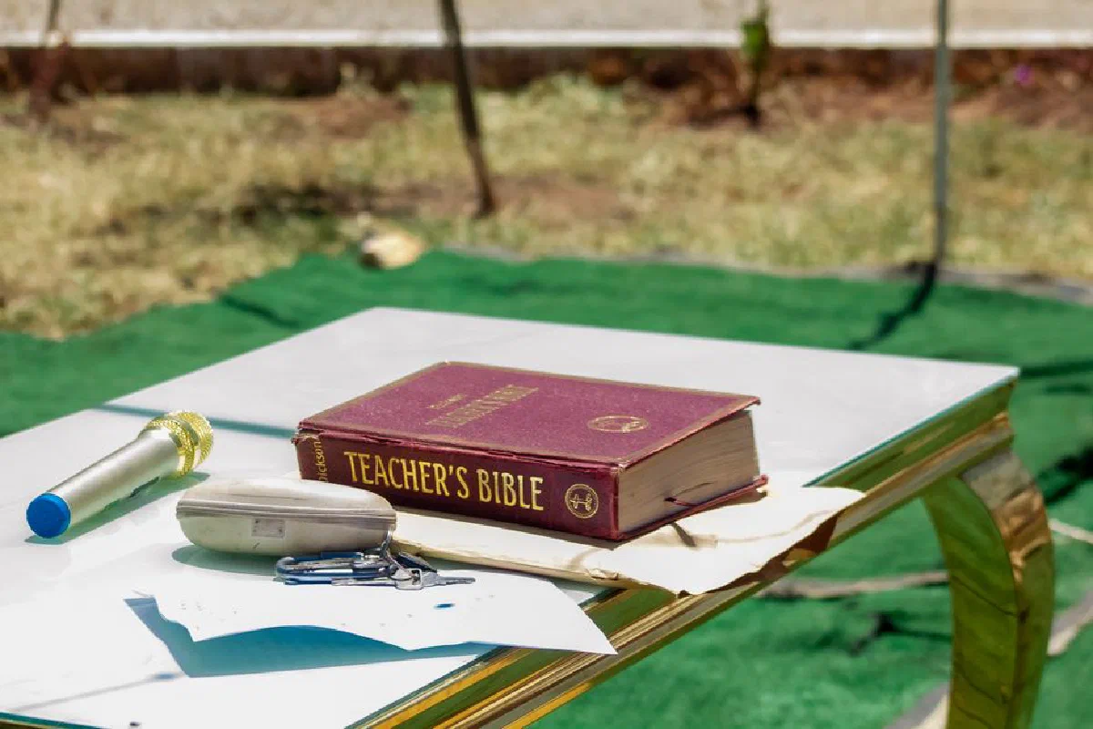 Outdoor table setup with a Teacher's Bible and microphone. Ideal for educational or religious themes.