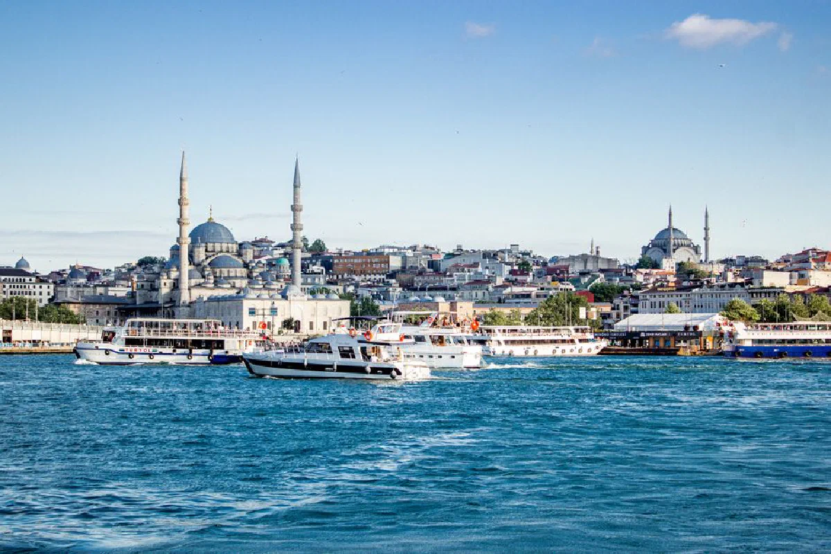 View of Istanbul's riverfront with prominent mosques and boats under a clear sky.
