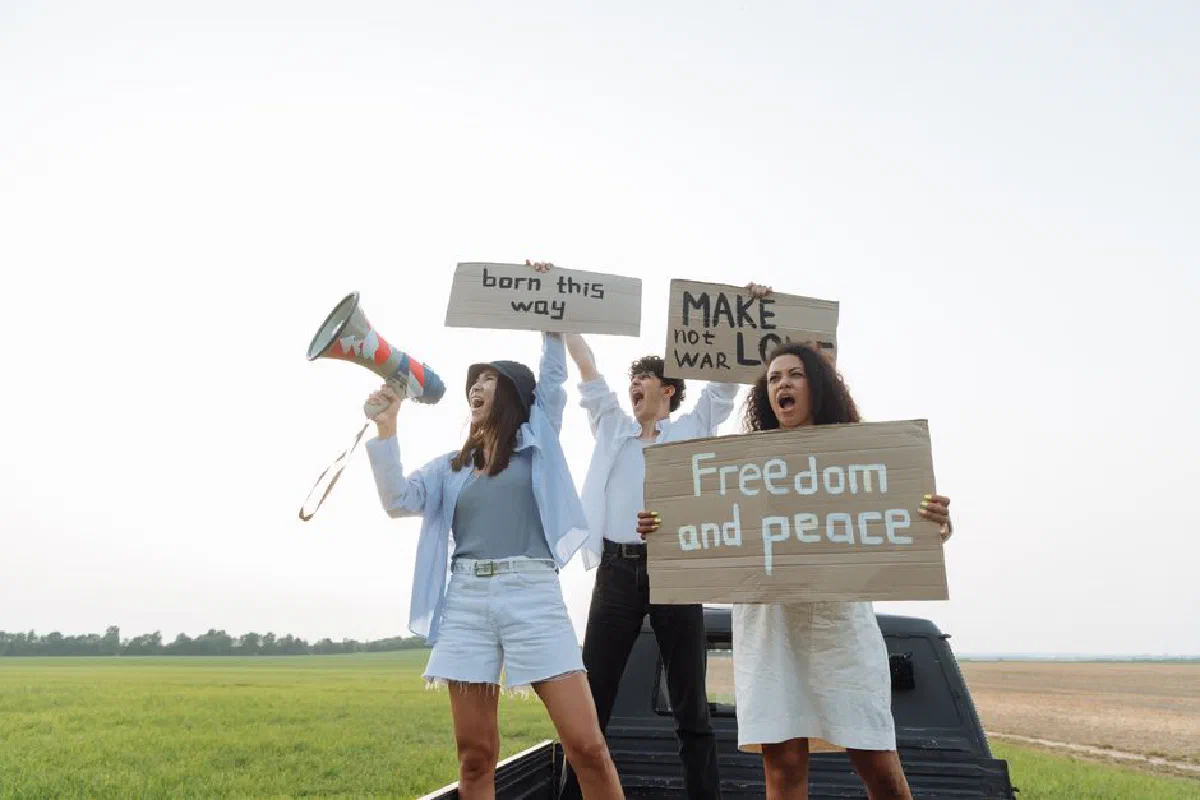 Group of young activists holding signs and megaphone at an outdoor protest.