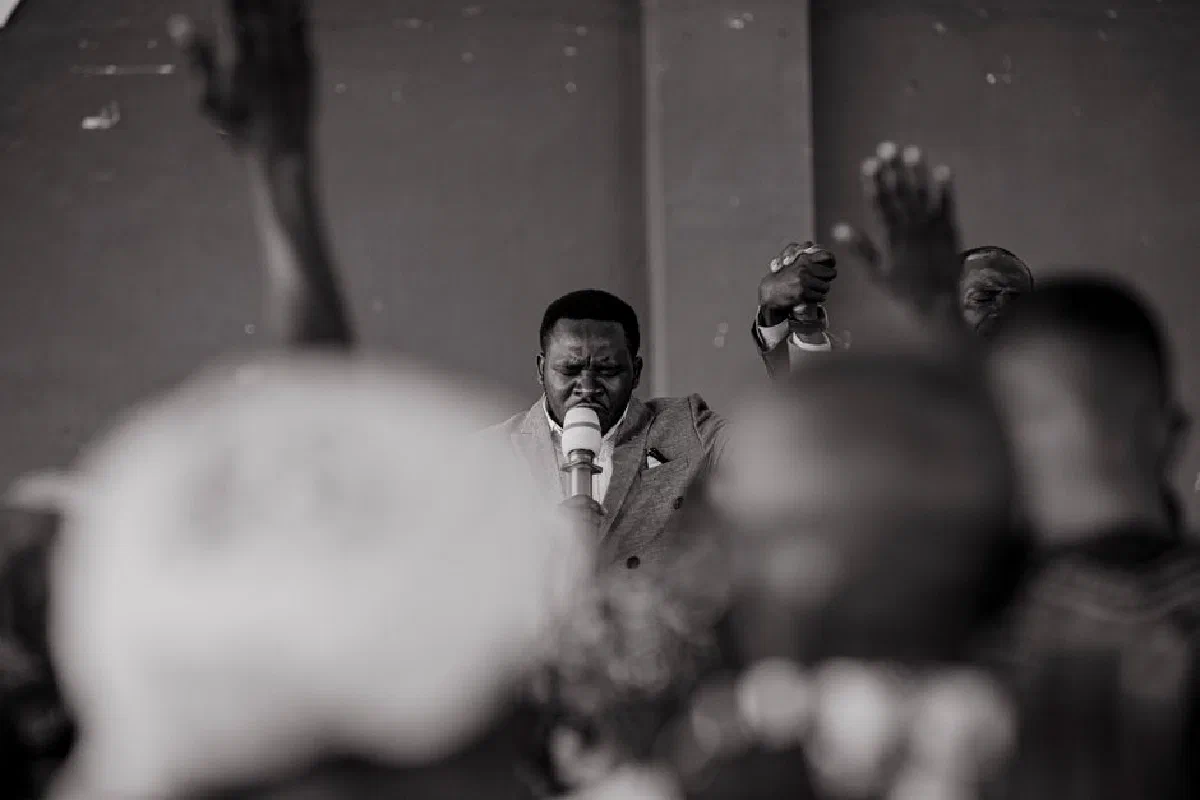 A passionate moment during a worship service with raised hands and a microphone.