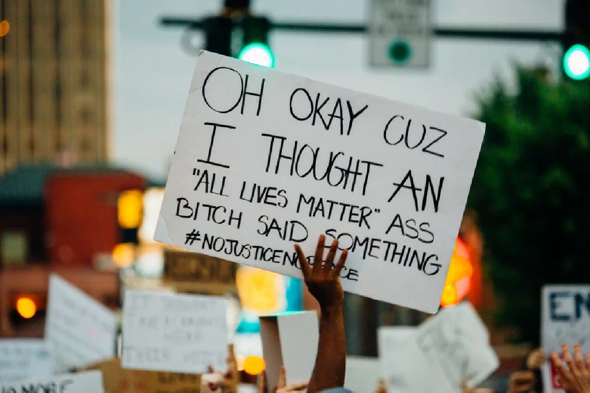 Crop unrecognizable African American person with banner protesting for human rights and against racism on street