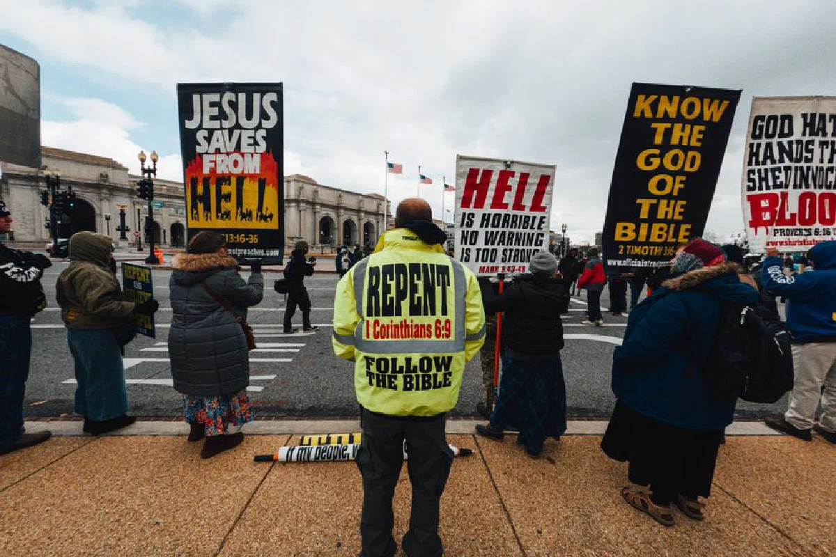 Back view of anonymous dissidents with religious messages on posters standing on walkway in town
