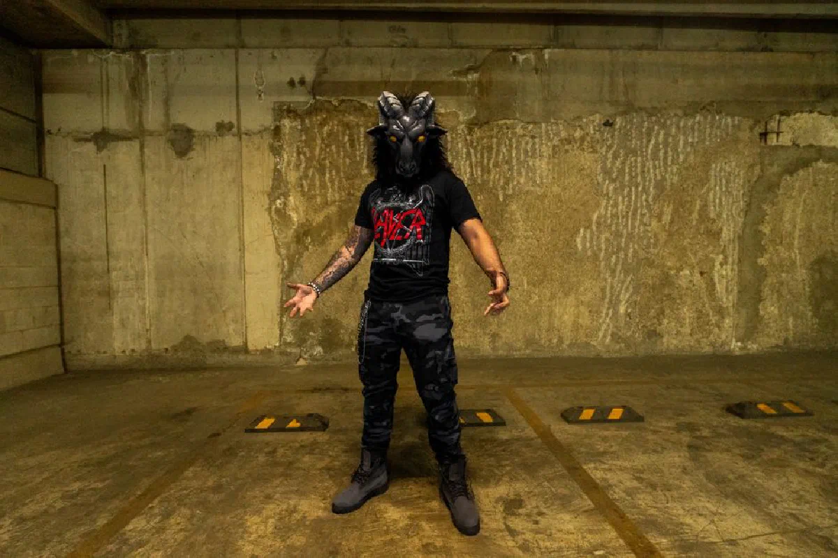 Dramatic portrait of a person in a devil costume, captured in a gritty urban garage setting.