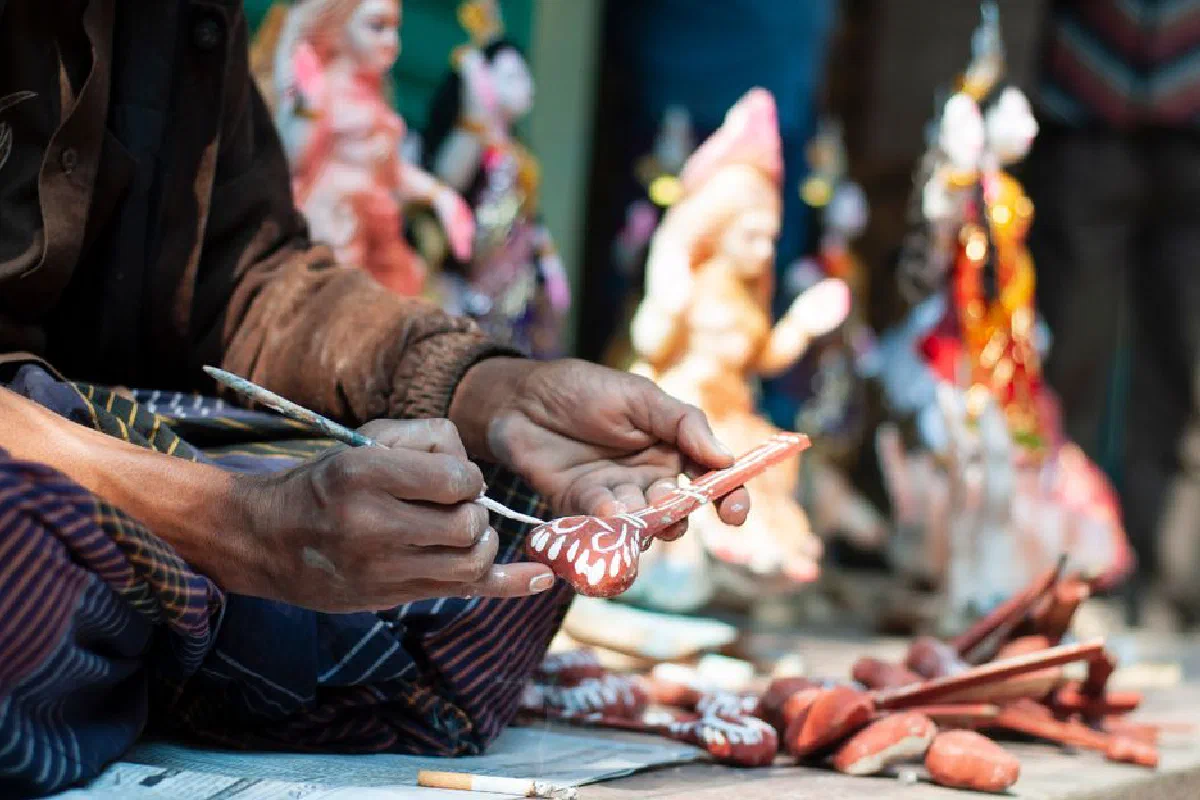 Artisan painting intricate designs on a clay sculpture with colorful details.