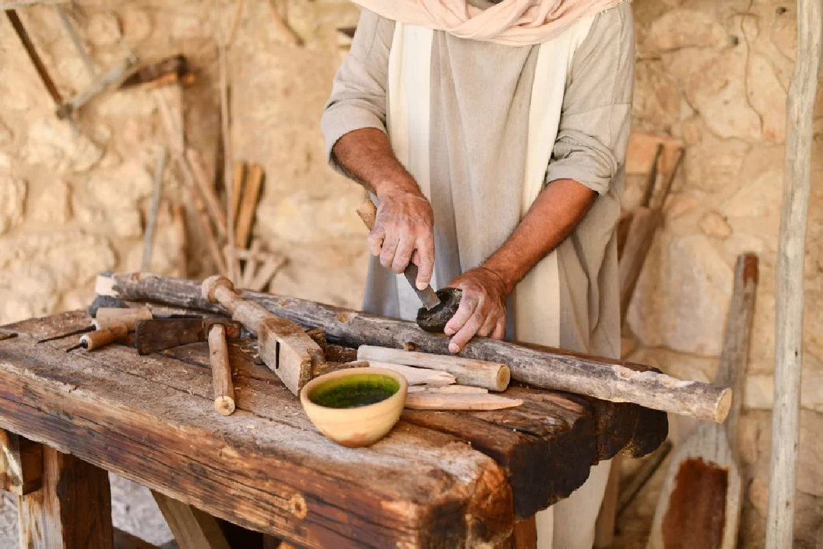 An artisan works skillfully with wooden tools in a rustic workshop environment.