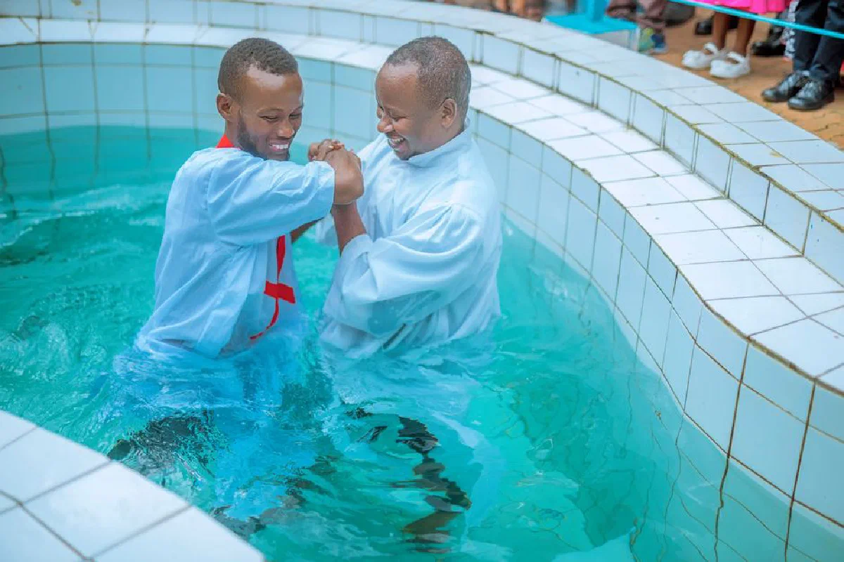 Two men celebrating a baptism ceremony in a tiled outdoor pool.