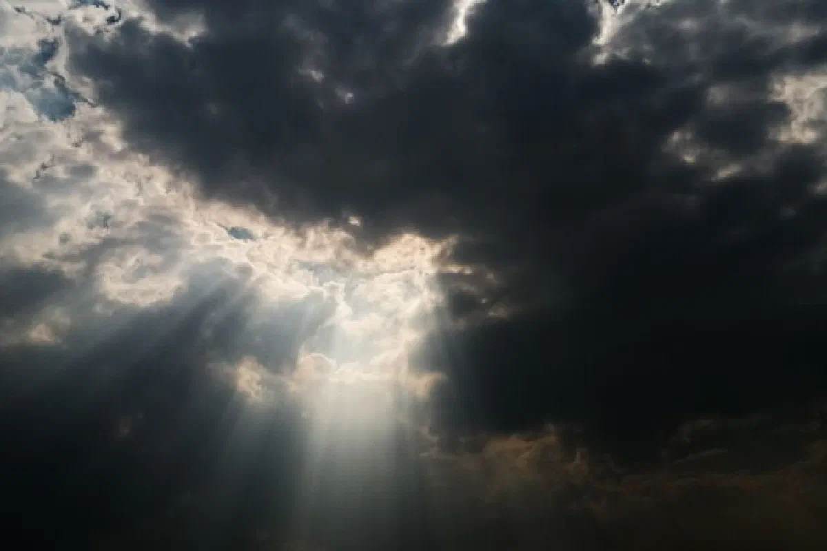 Dramatic sky with sun rays piercing through dark clouds, creating a celestial atmosphere.