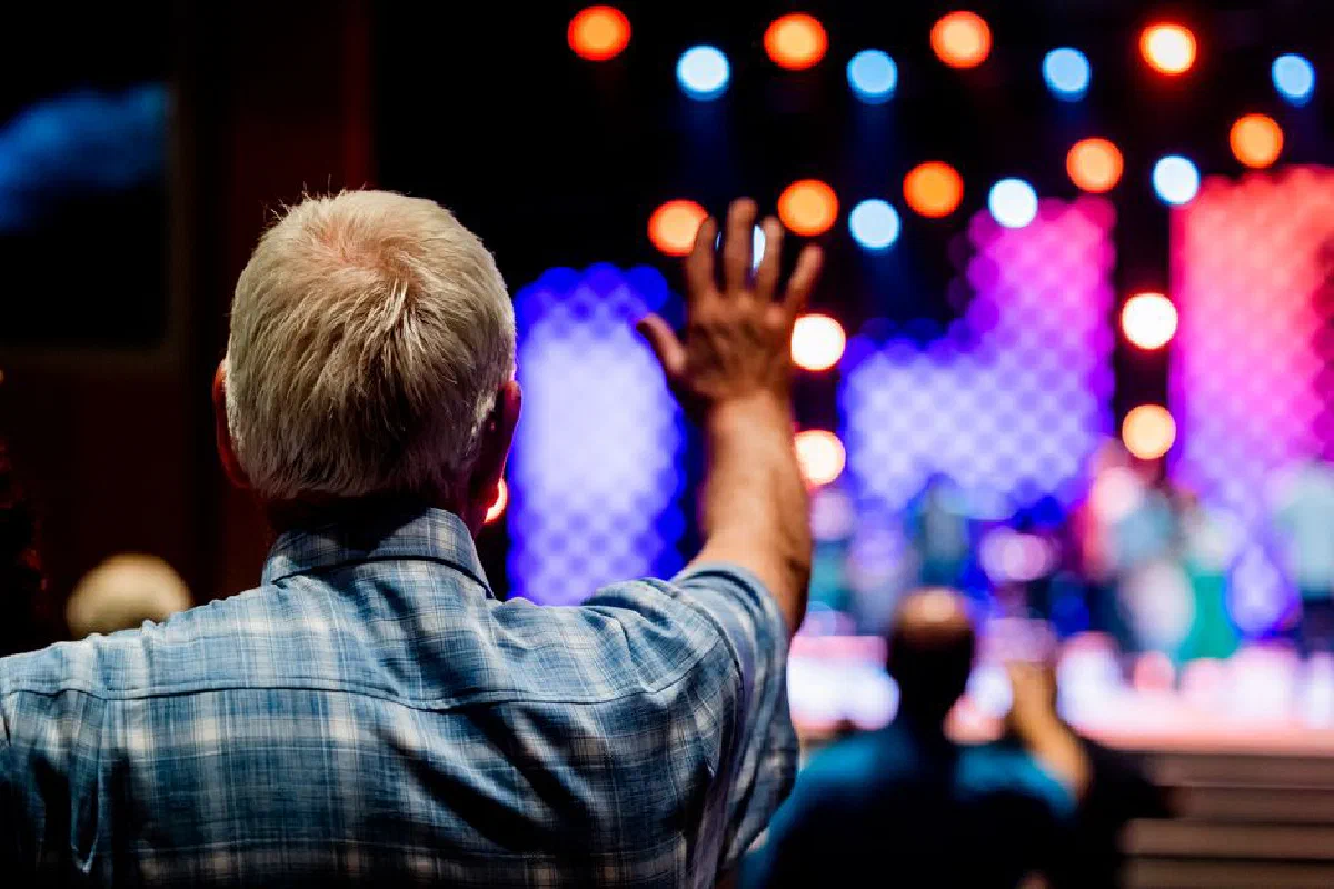 Senior man enjoying a concert with vibrant stage lights and a lively atmosphere.