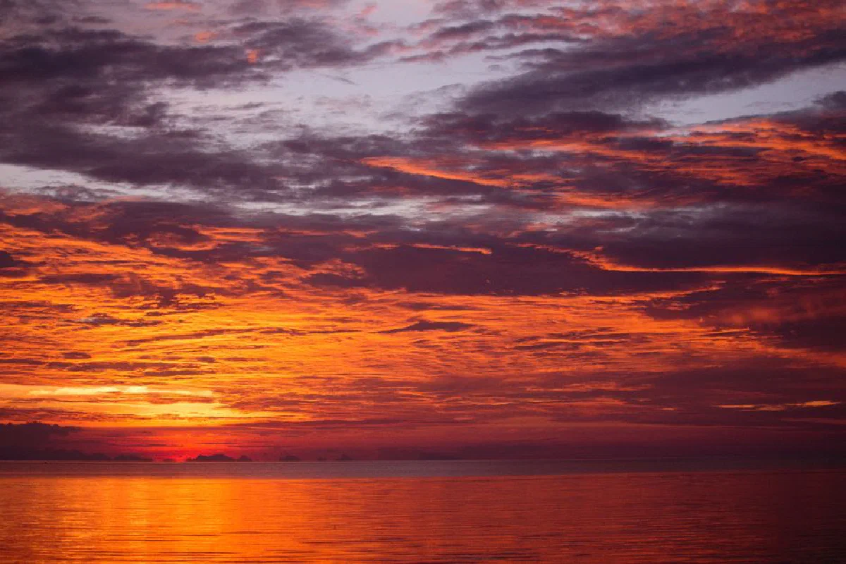Beautiful orange and purple sunset over the calm ocean with dramatic clouds.