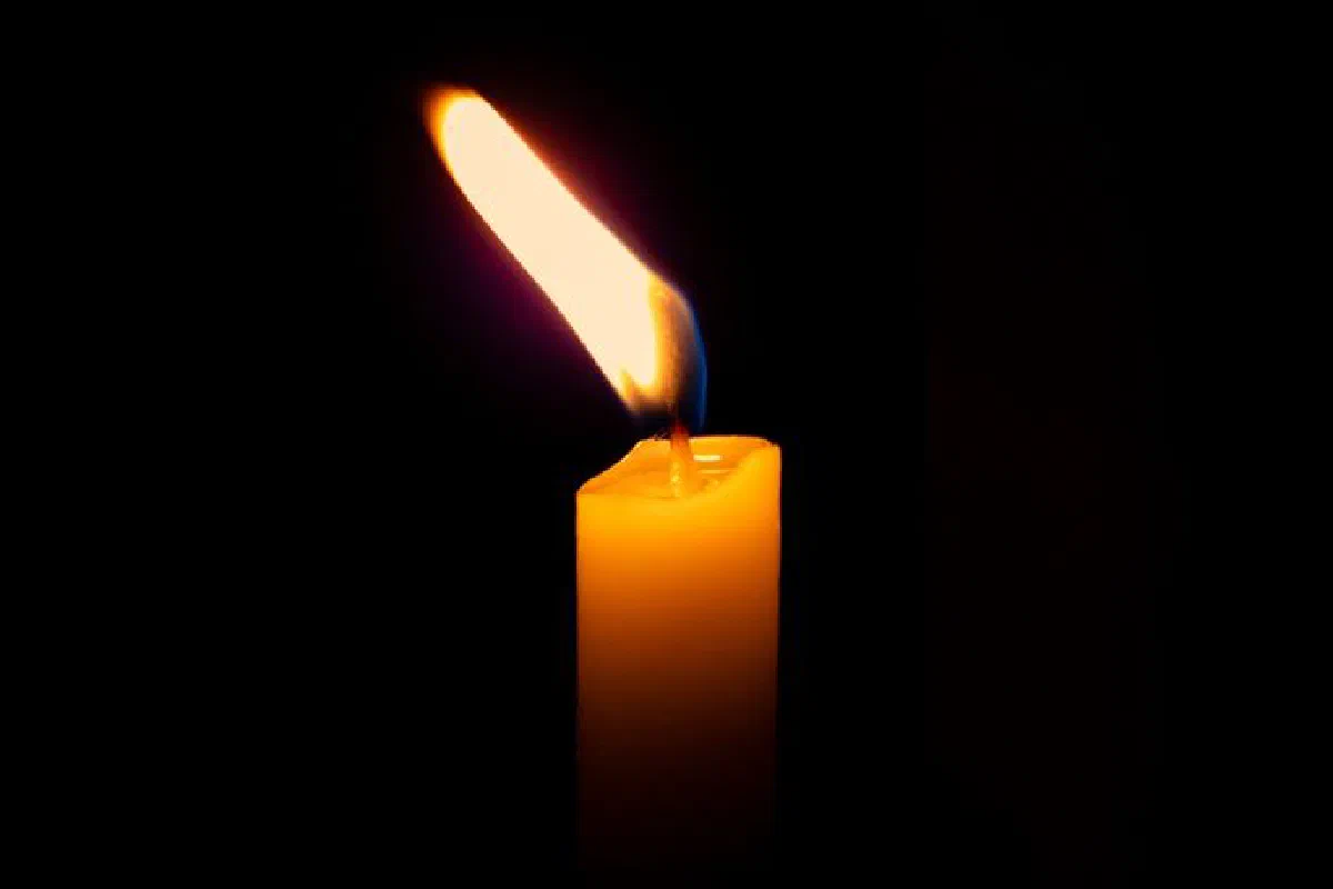A close-up of a solitary candle flame glowing in darkness, creating a cozy and reflective atmosphere.