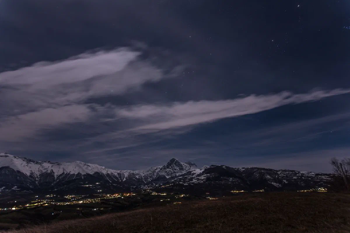 Scenic view of snow-capped mountains and a starry night sky, perfect for landscape enthusiasts.