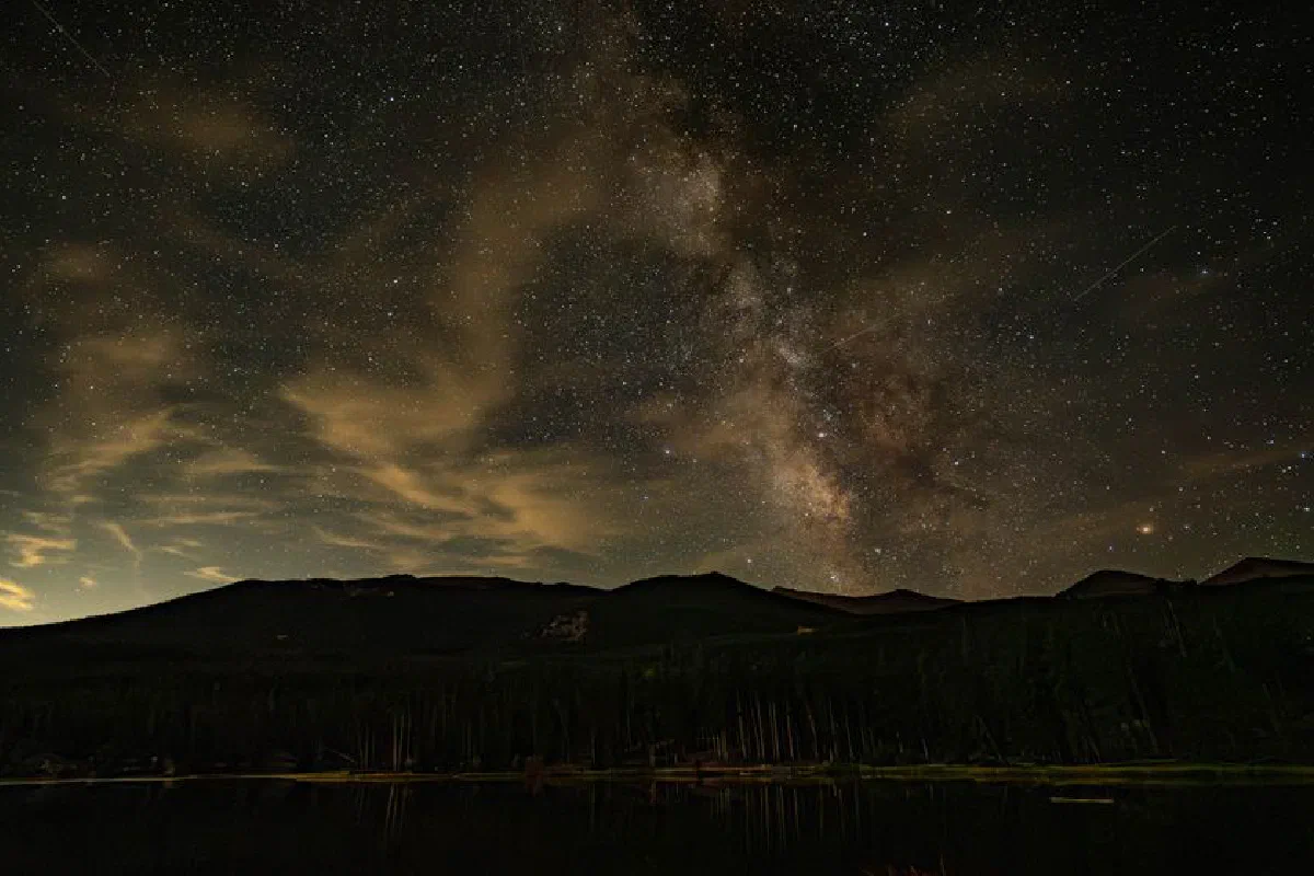A breathtaking view of the Milky Way galaxy illuminating the night sky over a silhouette of mountains.