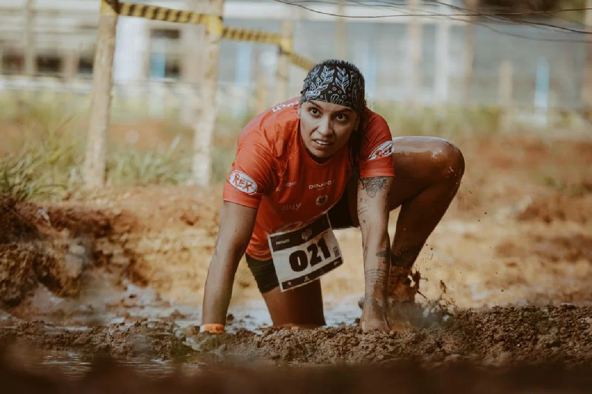 A determined female athlete in a muddy obstacle race, showing grit and focus.