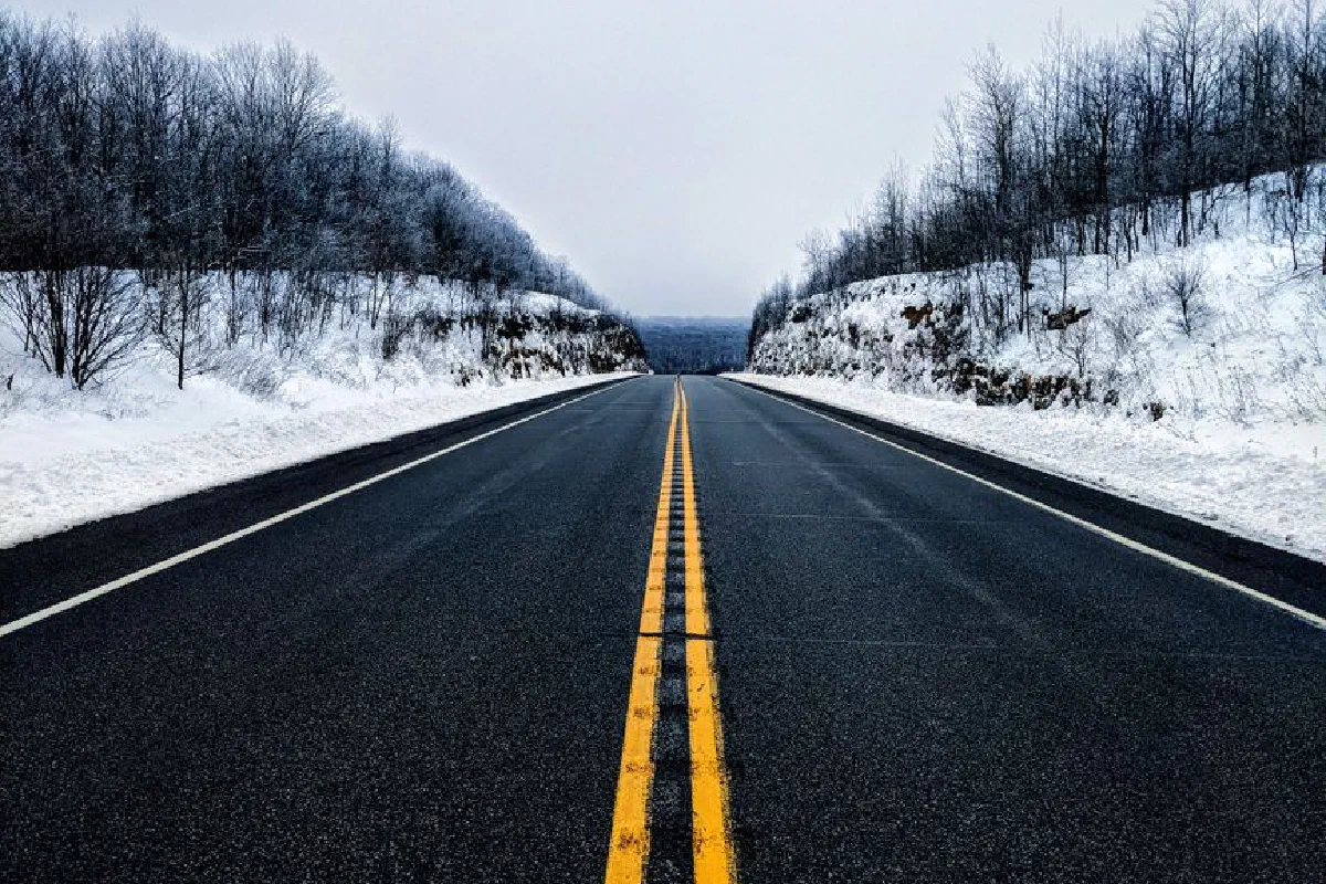 A quiet winter highway stretching through a snowy Pennsylvania forest. Perfect symmetry and seasonal beauty.