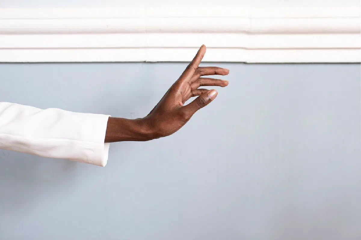 A graceful hand gesture against a light blue wall, suggesting communication and expression.