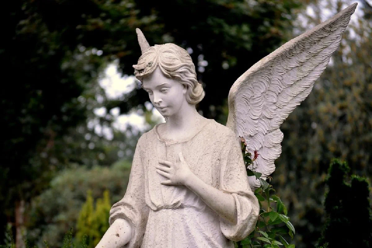 A tranquil angel statue with wings, captured in a lush Bocholt garden.