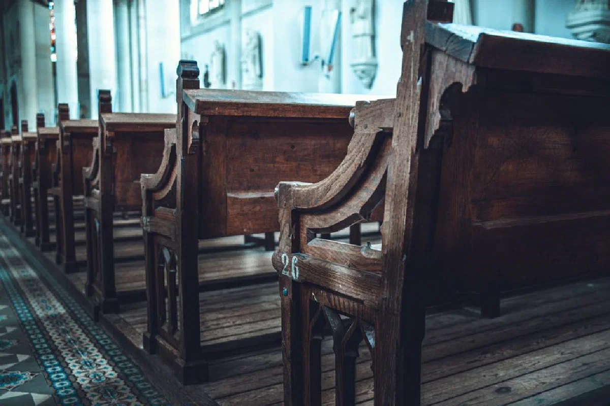 A serene view of traditional wooden church pews aligned in a sunlit interior.