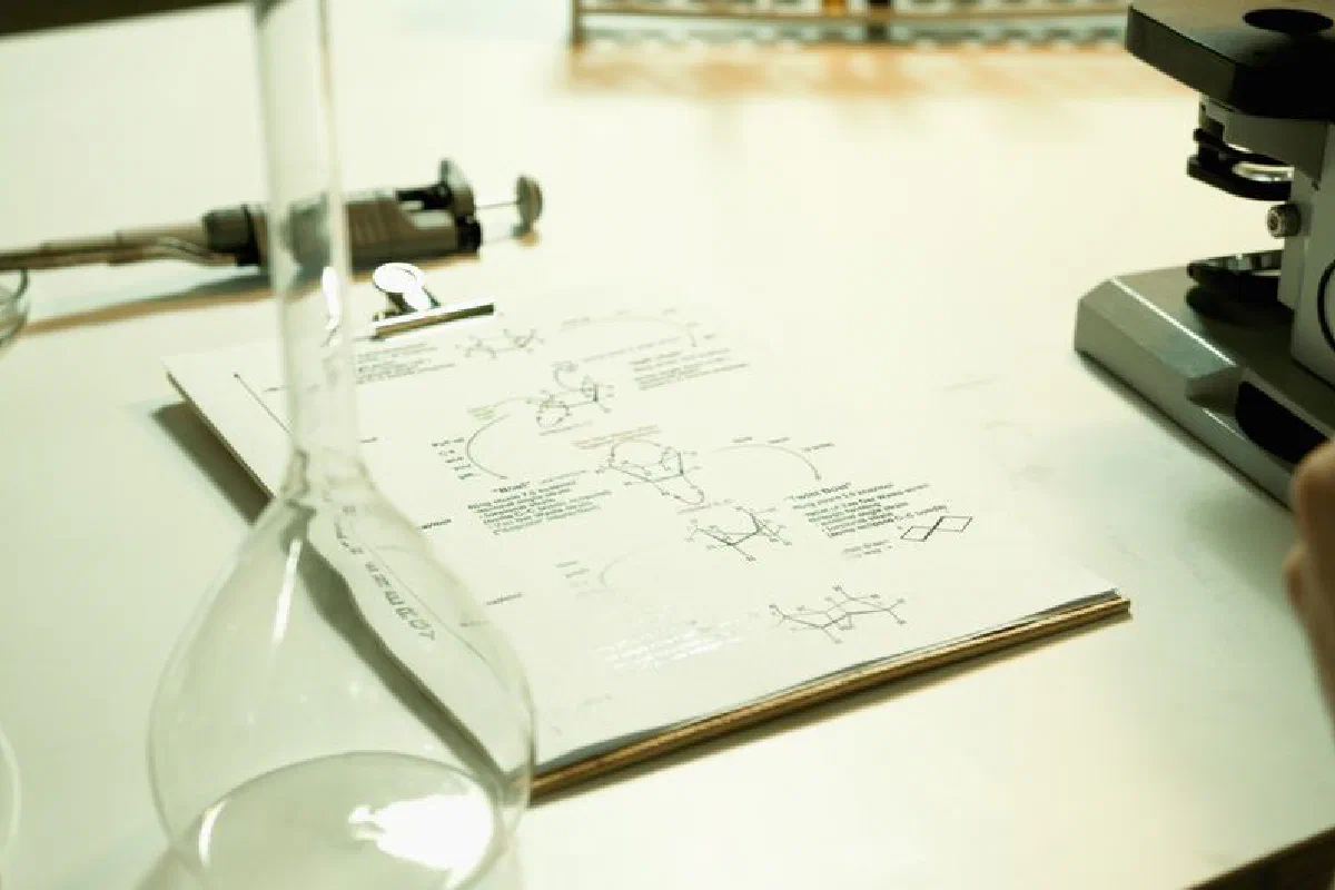 Close-up of a laboratory setup with documents, beaker, and microscope on a table.