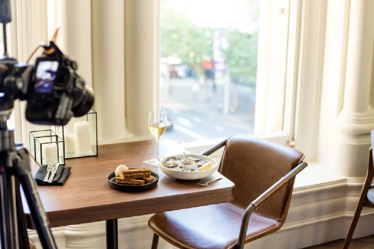 Modern dining table with food and camera setup by a window, perfect for food photography.