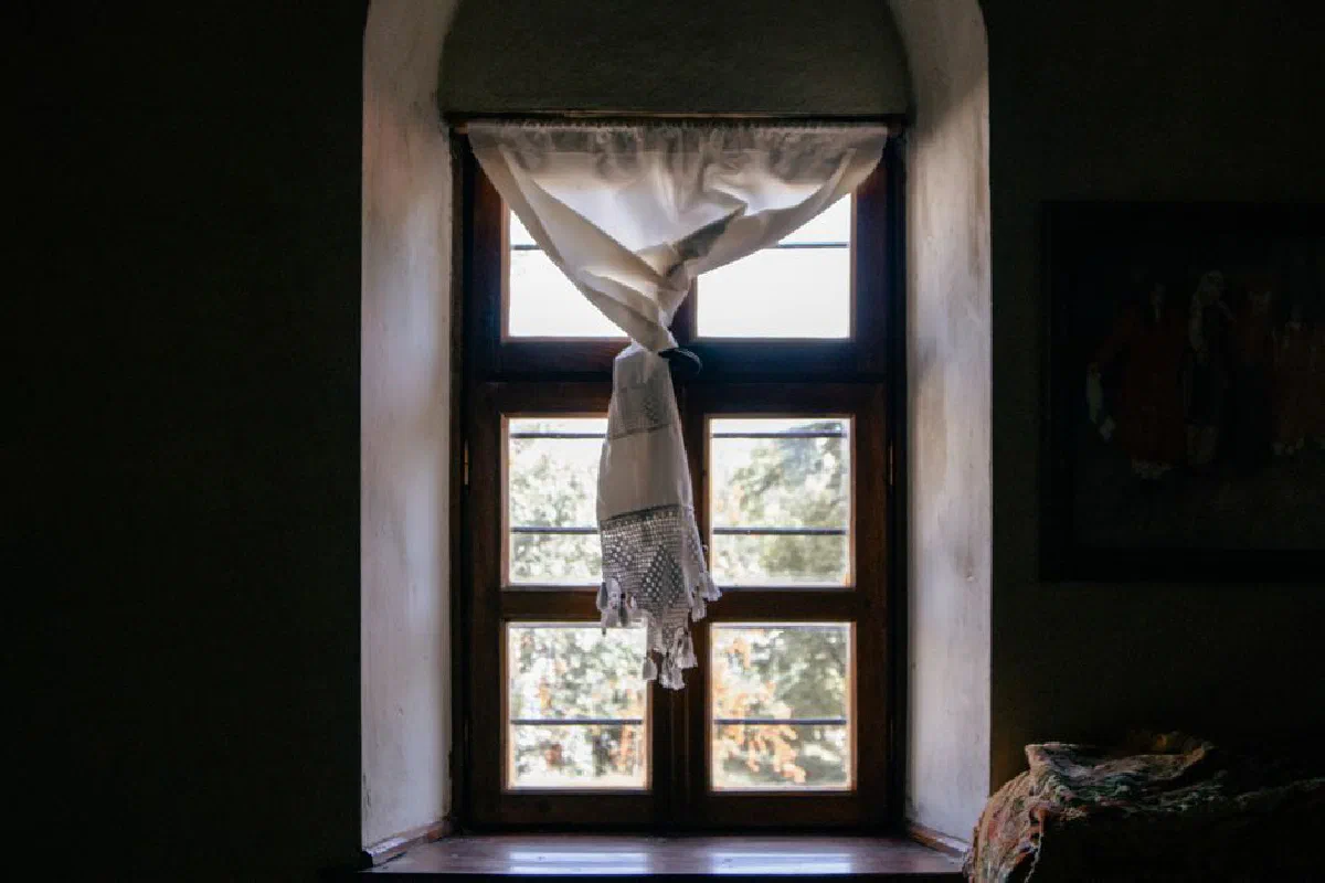 Charming window with sunlight streaming through vintage curtains in Elazığ, Türkiye.