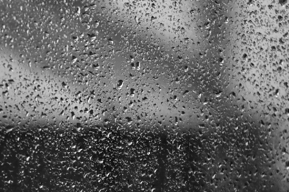 Close-up of raindrops on window glass with a defocused background, creating a textured look.