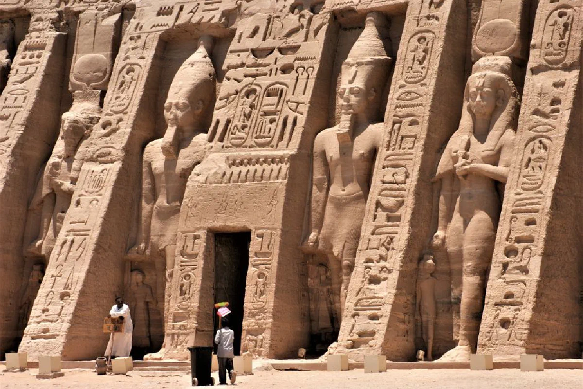 Exterior view of an ancient Egyptian temple featuring hieroglyphics and carved statues.