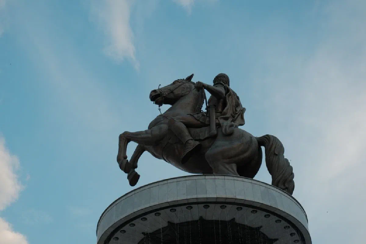 Majestic bronze statue of Alexander the Great on horseback in Skopje, with a clear blue sky backdrop.