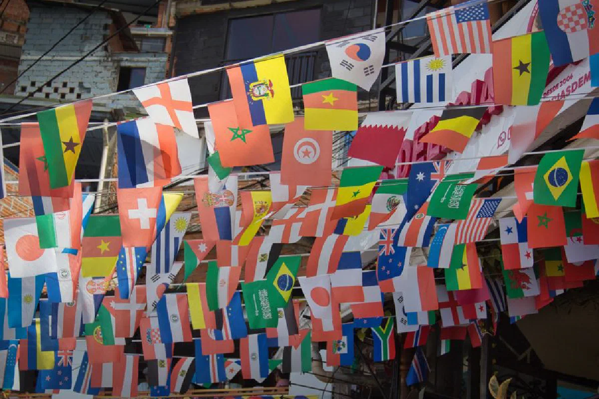 Colorful display of multiple international flags strung across buildings outdoors reflecting global unity.