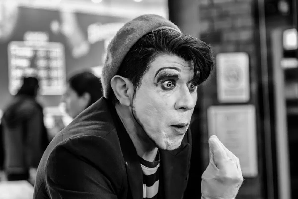 A captivating black and white portrait of a mime artist performing indoors, showcasing expressive facial expressions and makeup.