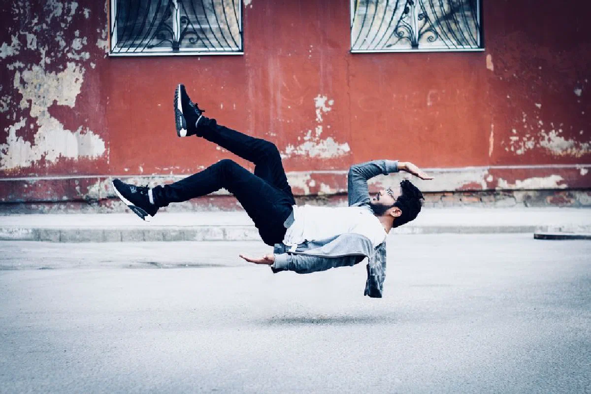 A man levitates in an urban setting, showcasing artistic photographic skills.