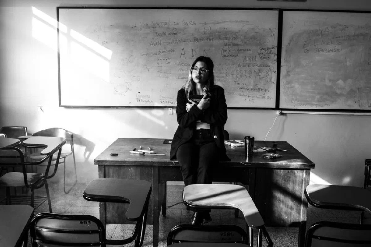 A thoughtful moment captured in a university classroom featuring a lecturer sitting on a desk, Buenos Aires.