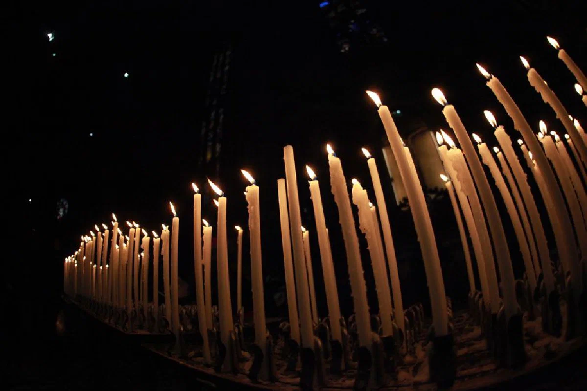 A row of lit candles glowing warmly in a dark setting, creating a serene atmosphere.