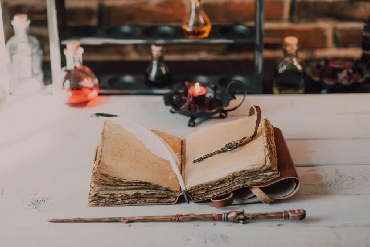 An enchanting scene featuring a vintage spellbook with quill and wand on a wooden table, evoking witchcraft.