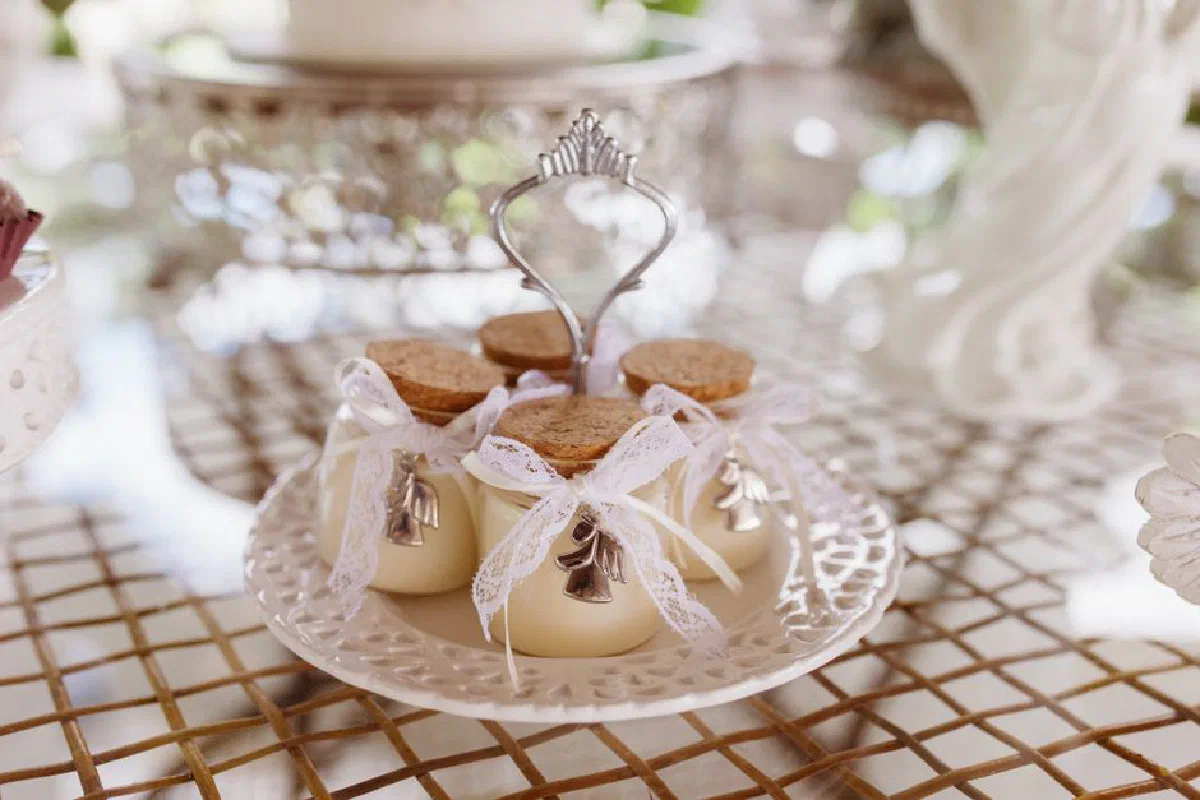 Beautifully arranged wedding favors with lace and bells on a decorative plate at a wedding setup.