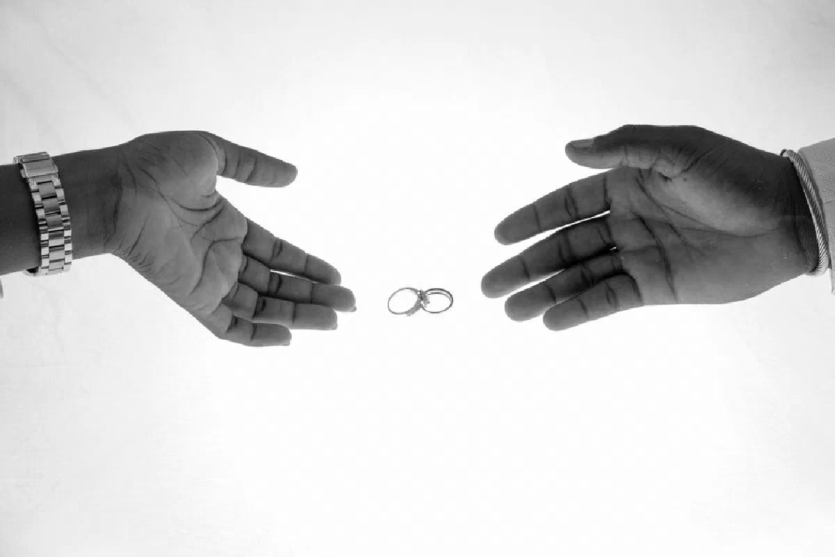 Two hands reaching towards each other with wedding rings in the center, symbolizing love and union.