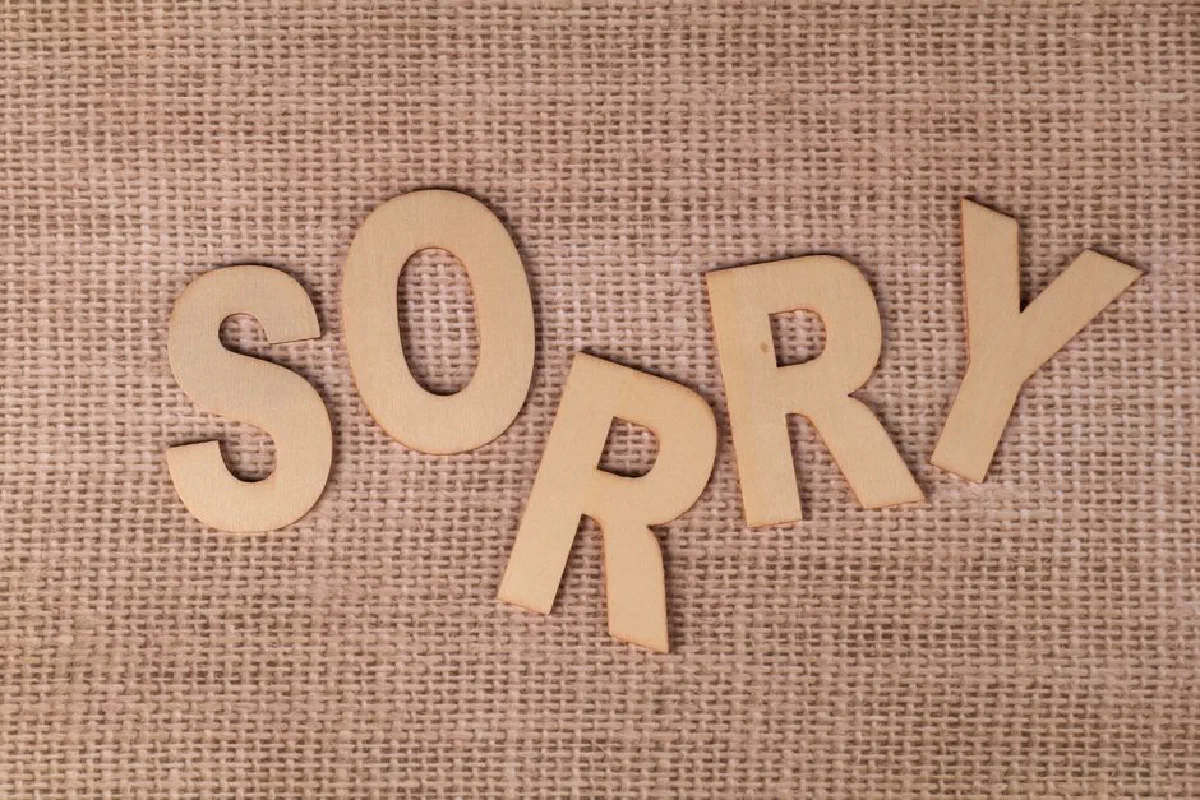 Wooden letters forming 'SORRY' on a burlap surface, offering a rustic apology vibe.