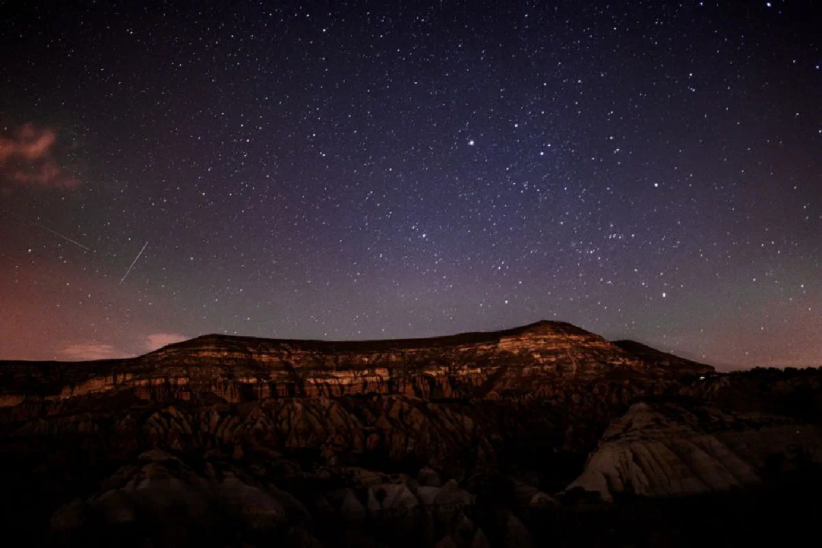 Breathtaking view of a star-filled sky over a rugged mountain range at night.