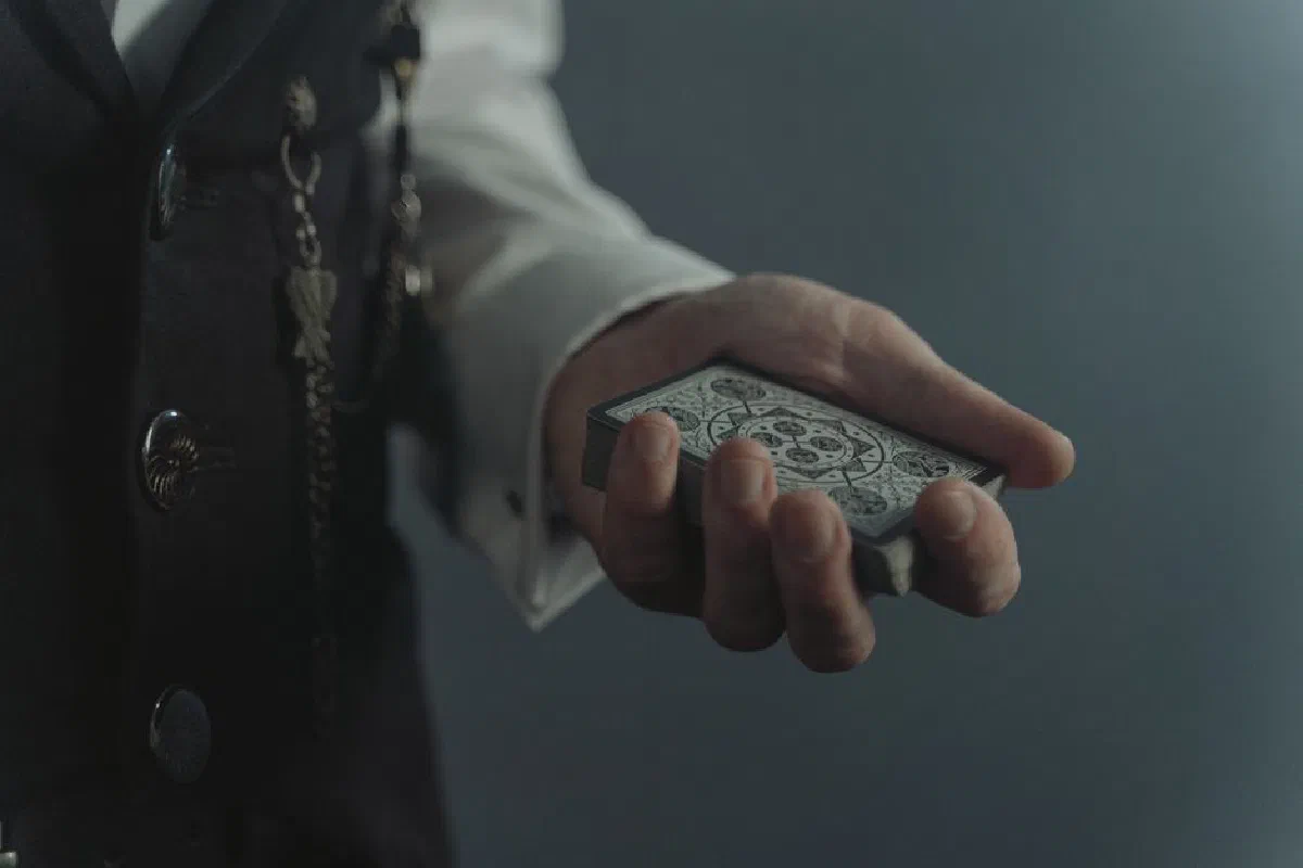 A magician's hand holding a detailed deck of cards, ready for a trick.