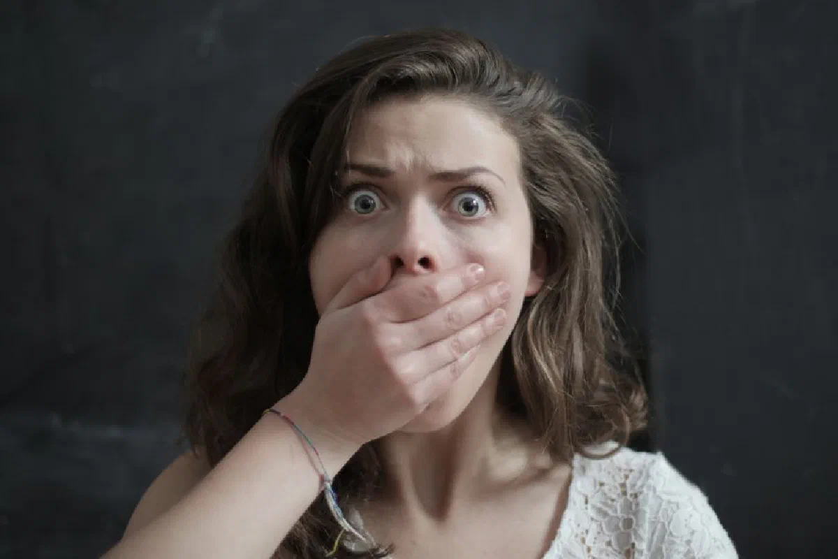 Close-up of a woman with a shocked expression, covering her mouth with her hand. Emotional and intense moment.