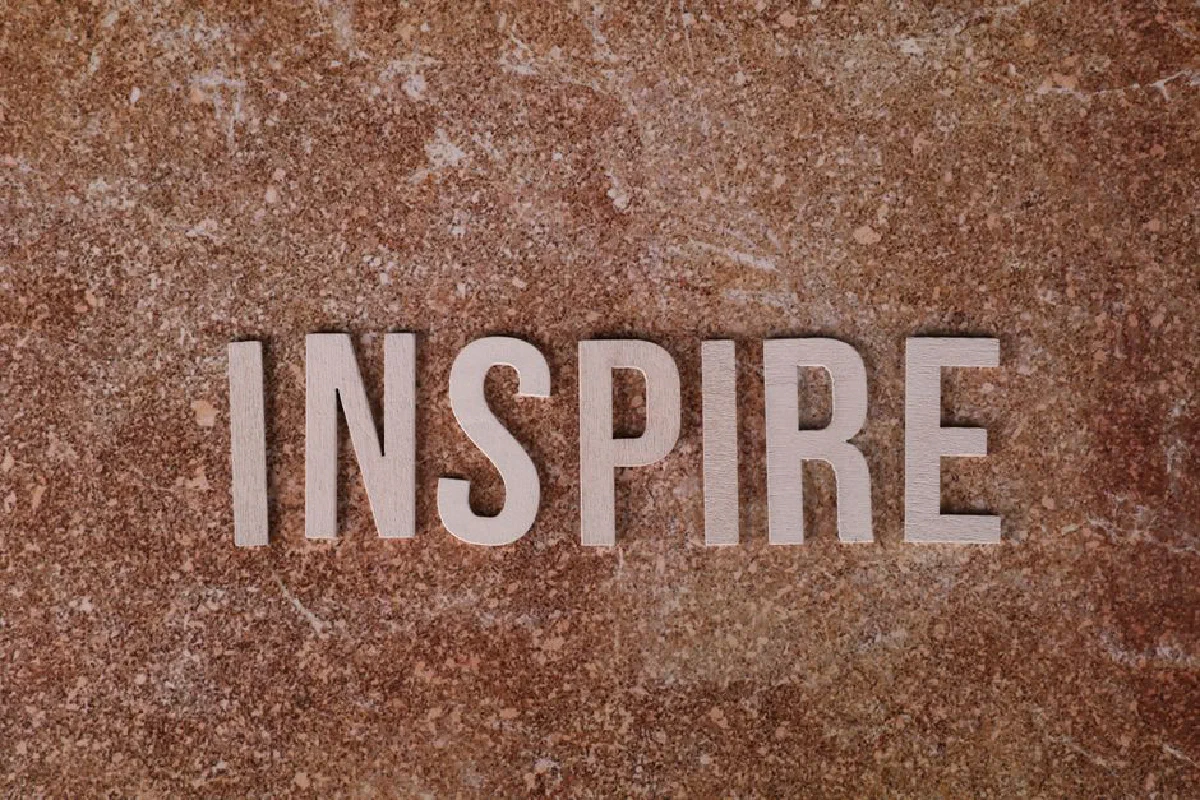 Inspirational word 'INSPIRE' on a textured stone background for motivation.