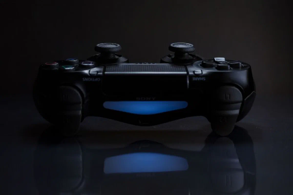 Close-up of a gaming controller with a soft blue light in a dark setting.