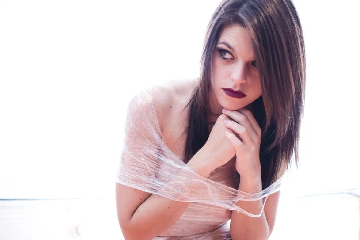 Portrait of a young woman wrapped in plastic looking thoughtful and pensive indoors.