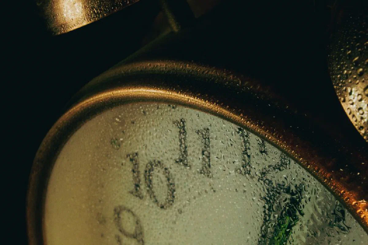 A detailed close-up of an alarm clock face covered with water droplets, creating a moody atmosphere.
