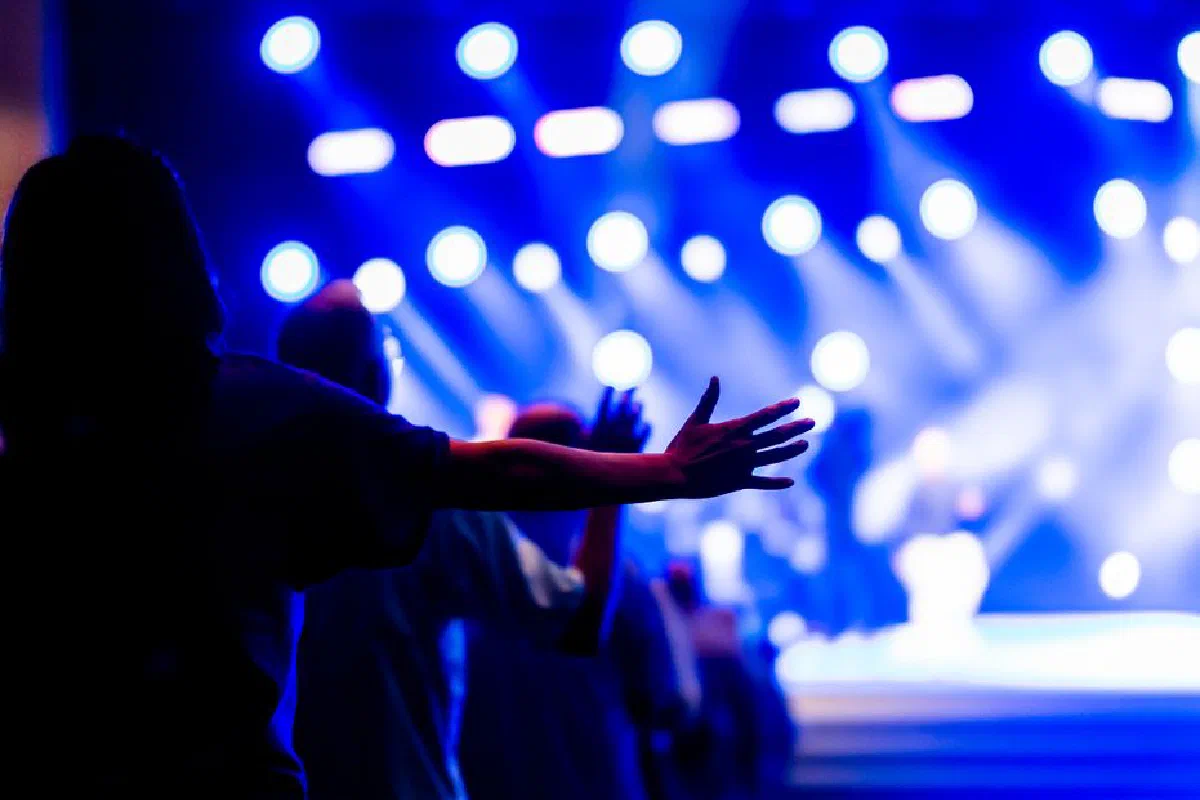 Vibrant concert scene with people raising hands, capturing the energy and spirituality of the moment.