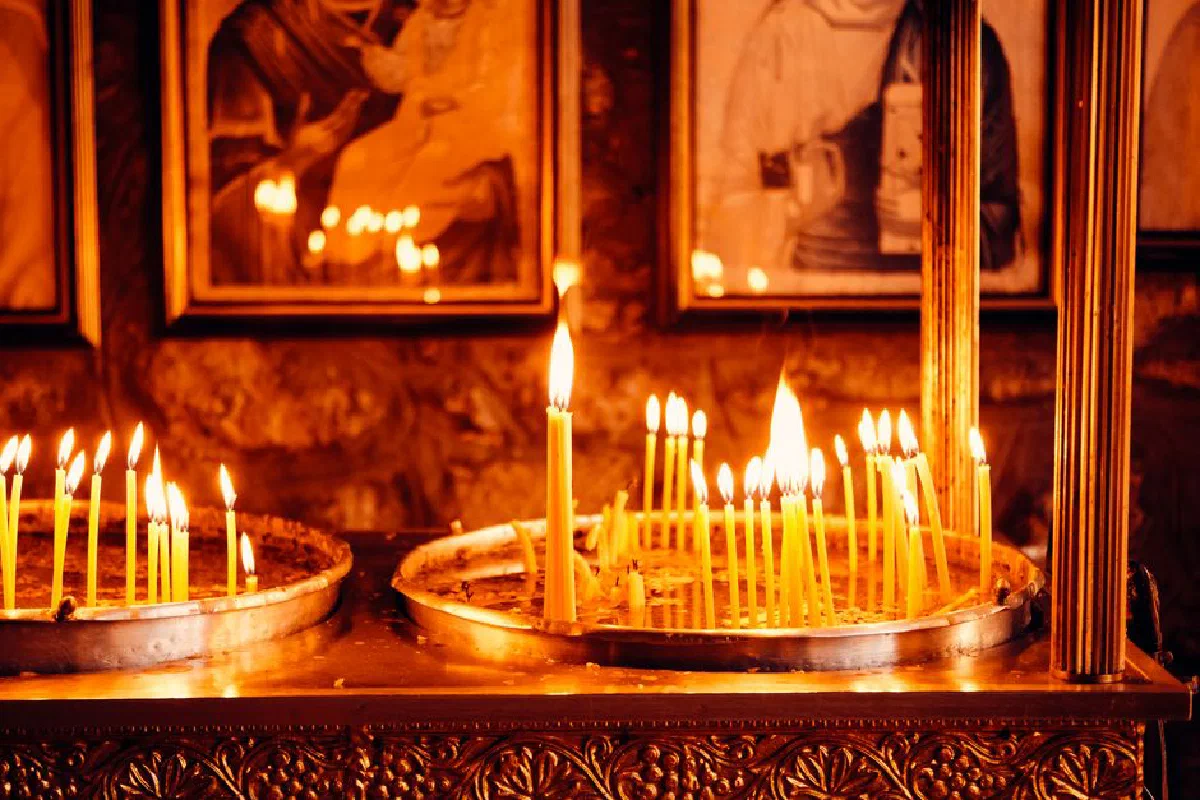 Warm candlelight illuminates an ancient chapel in Kuzey Makedonya, creating a serene atmosphere.