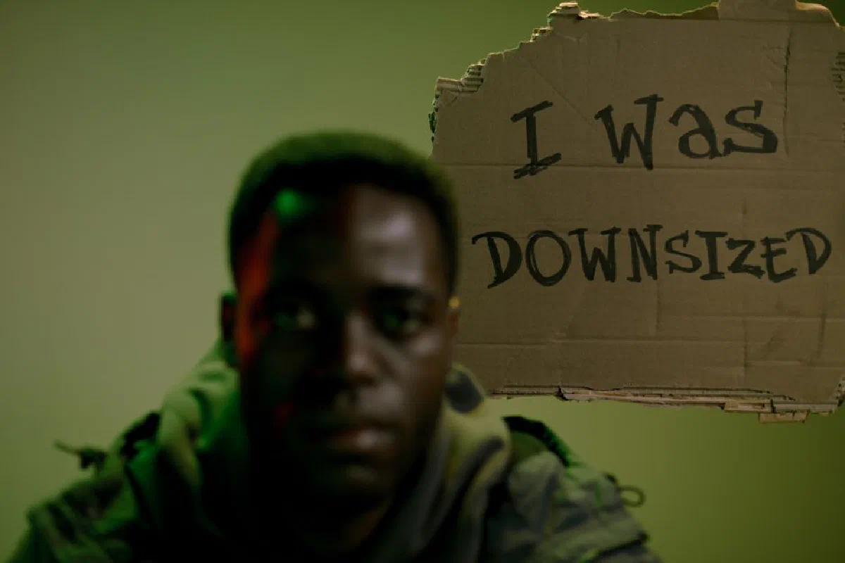 Close-up of man holding a cardboard sign that reads 'I Was Downsized'.